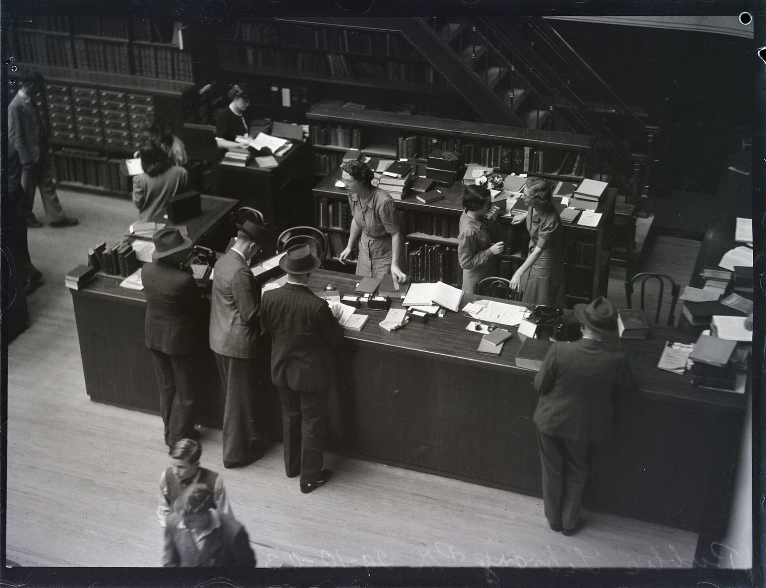 Readers gathered at a library desk, State Library of New South Wales, 1943